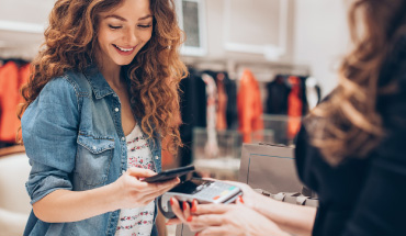 Woman holding her smartphone to pay for goods