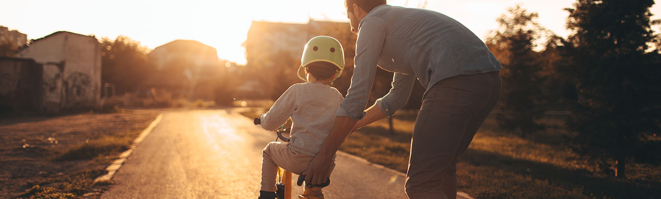 A dad helping his son learn how to ride a bike