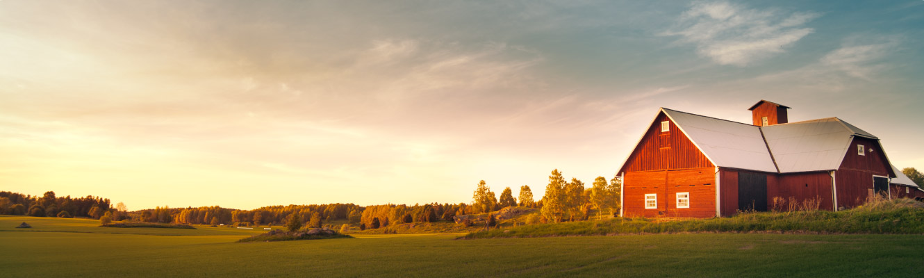 A large red barn set against a wide landscape