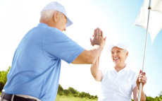A senior couple playing golf. They're high-fiving.